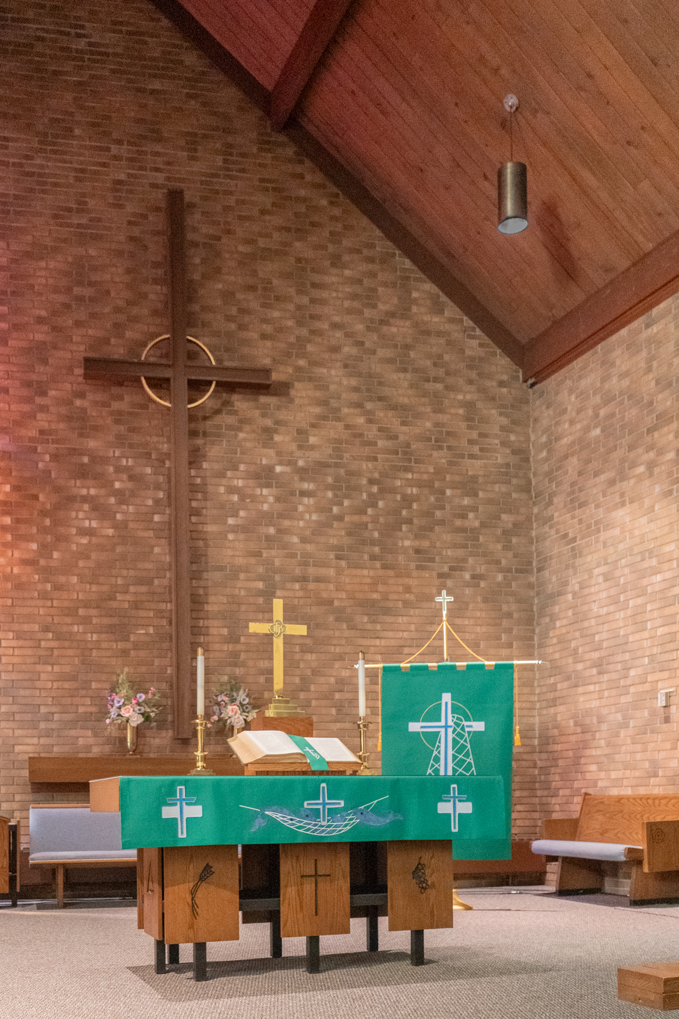 The pulpit with the cross on the back wall, and the altar in the foreground with green paraments.