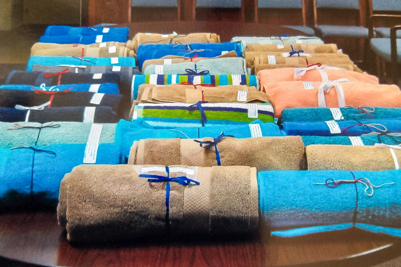 Towels of various colors wrapped into rolls and tied with ribbon laid out on a table.