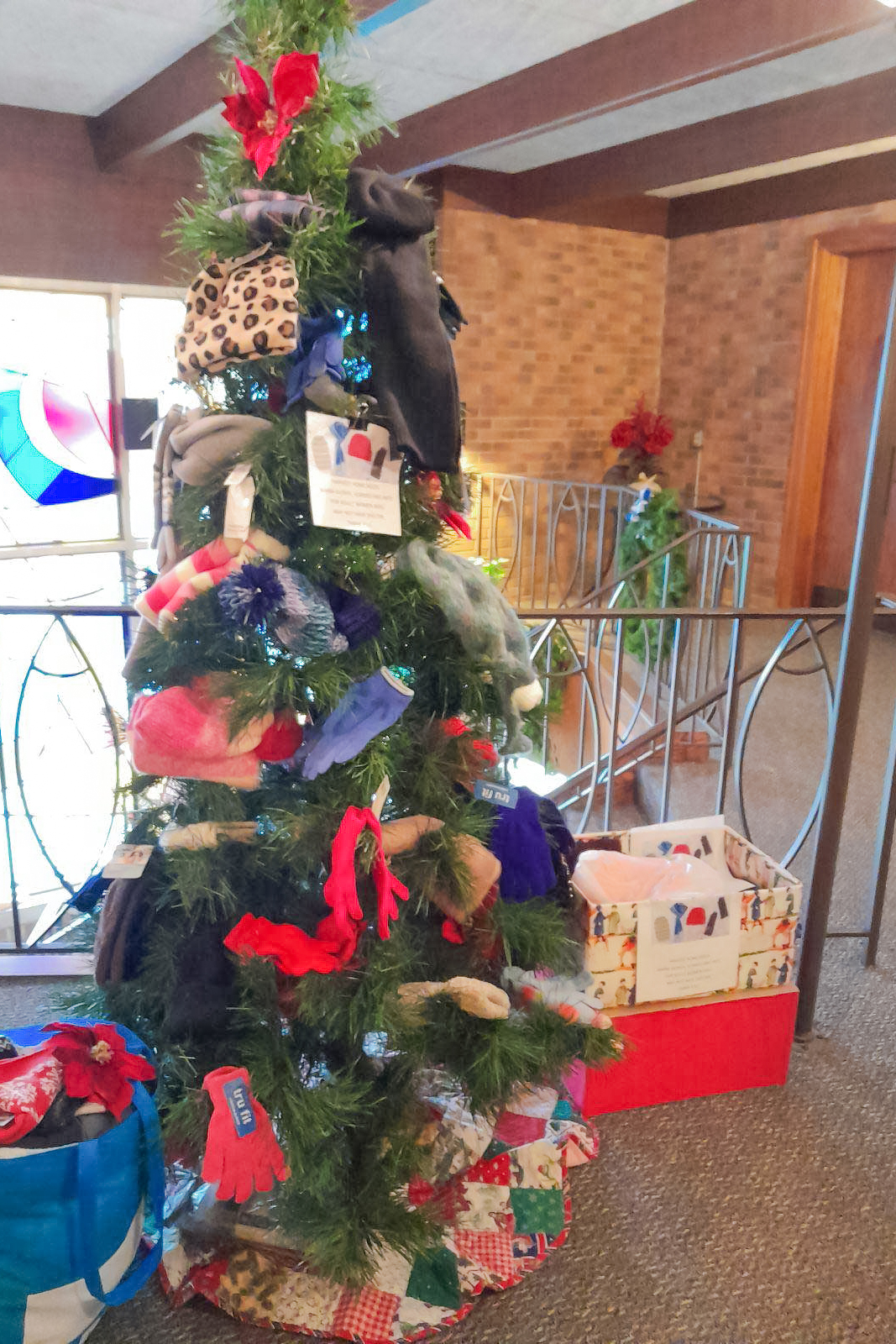 Hats, gloves, and other winter gear hung on a small Christmas tree for donations.