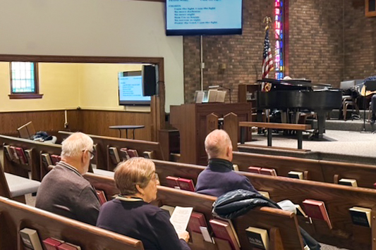 Three members of the congregation sitting in the pews for Sunday service.